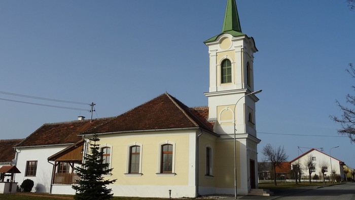 Kleine Kirche mit hohem Turm und grünem Dach in ländlicher Gegend