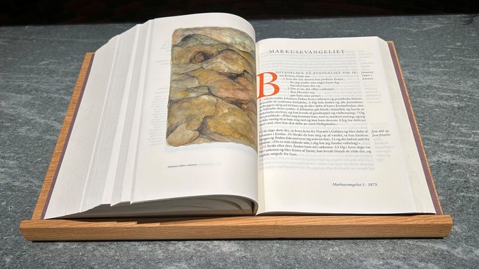 Åben bog på et bord med et stort bogstav B og et billede.