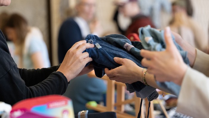 Zwei Personen betrachten Kleidung auf einem Tisch.