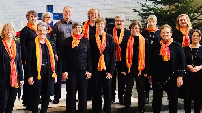 Gruppe von Personen mit aufeinander abgestimmten Schals, die gemeinsam im Freien in der Nähe eines Gebäudes posieren.