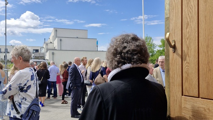 Asta Gyldenkærne kigger ud på kirkepladsen ved Vejleå Kirke