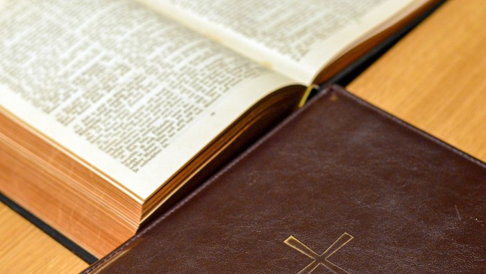 Offenes Buch mit Kreuz auf Einband auf Holzoberfläche