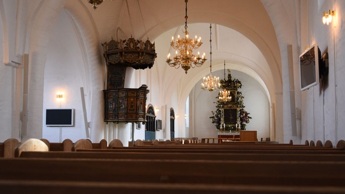 Indenrigs af kirke med høje hvelvede og belysninger