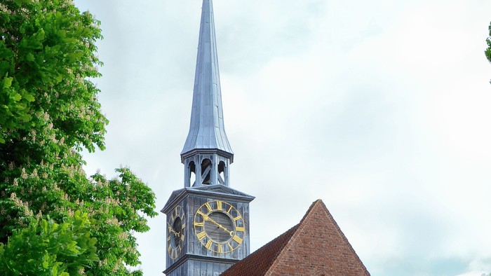 En rød murstenskirke med tårn og klokke.