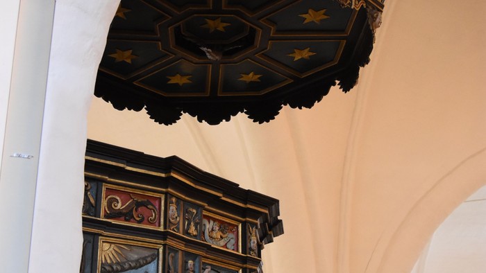 Historisk prædikestol inde i en prægtigt udsmykket kirke med indviklede udskæringer og religiøs kunst.