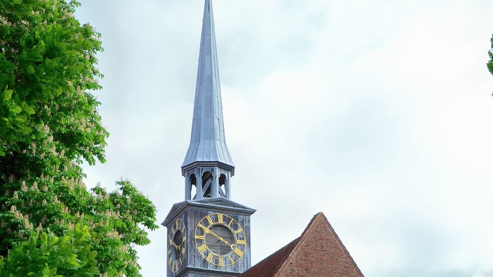 En rød murstenskirke med tårn og klokke.