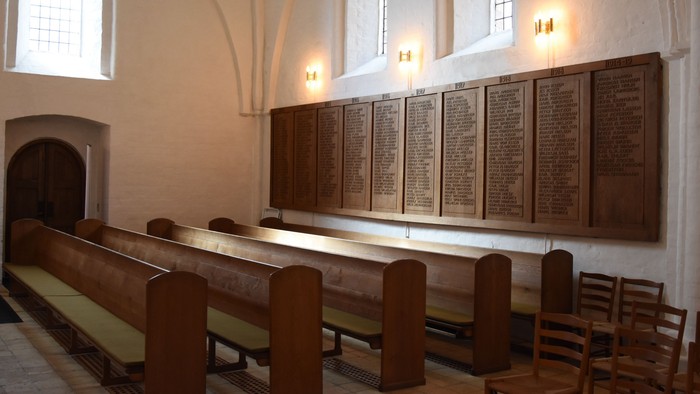 Kirken indeholder træbænke og mindetavler på væggen