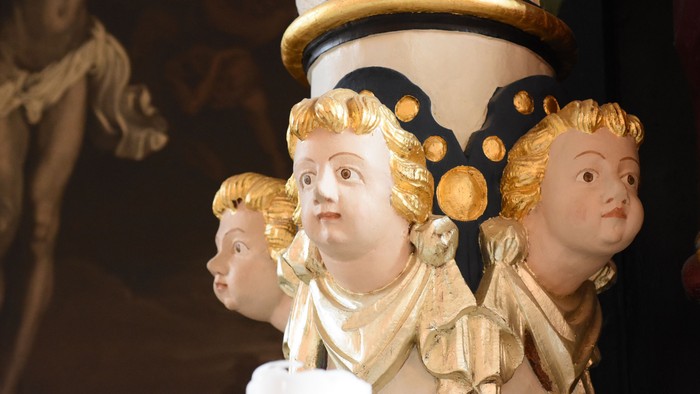 Indviklede gyldne religiøse statuer, smykket med prægtige kroner og glorier, i en detaljeret arkitektonisk ramme.