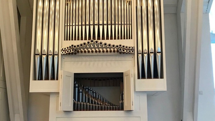 Elegant pibeorgel med flere piberækker i et stort, minimalistisk kirkeinteriør.