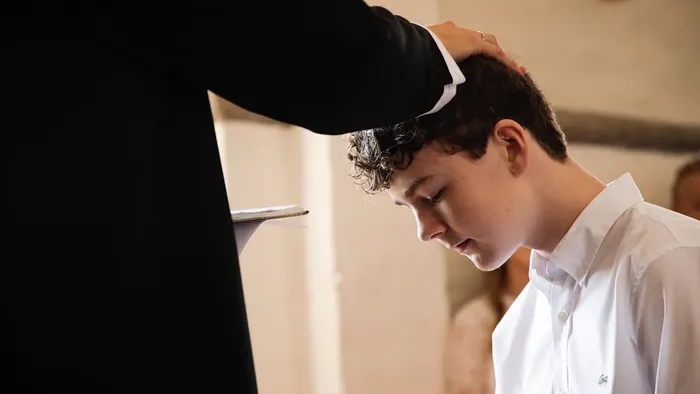 Præsten lægger hånd på konfirmanden