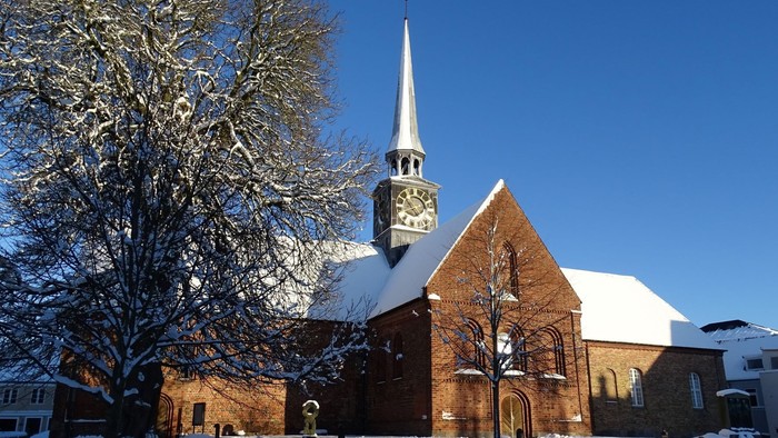 En snede kirke med klokketårn og en især snebelagt træ foran