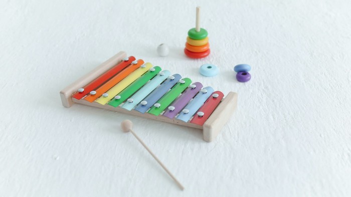 Billedet viser et bunt legetøj med en xylofon, en pyntestange og en kugle.