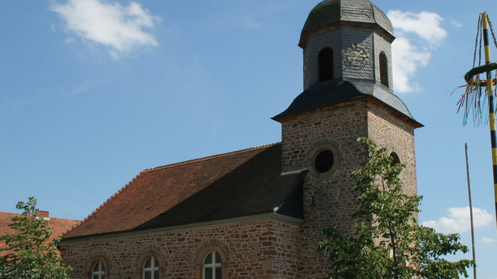 Kirchengebäude mit hohem Turm und spitzem Dach unter blauem Himmel