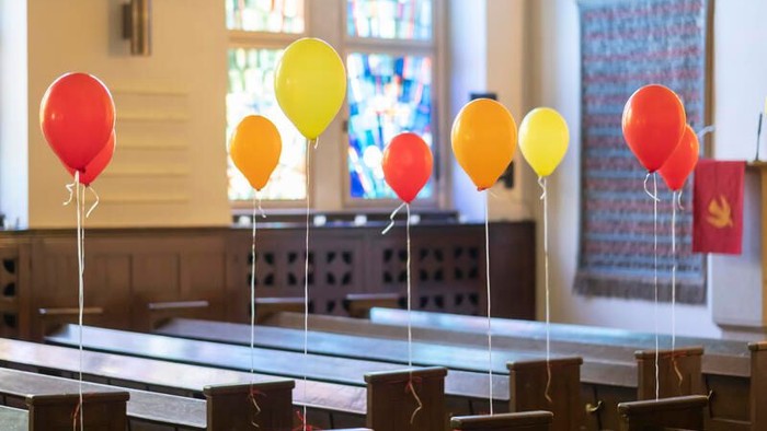 Bunte Luftballons, die an hölzernen Kirchenbänken in einer Kirche oder Kapelle befestigt sind.
