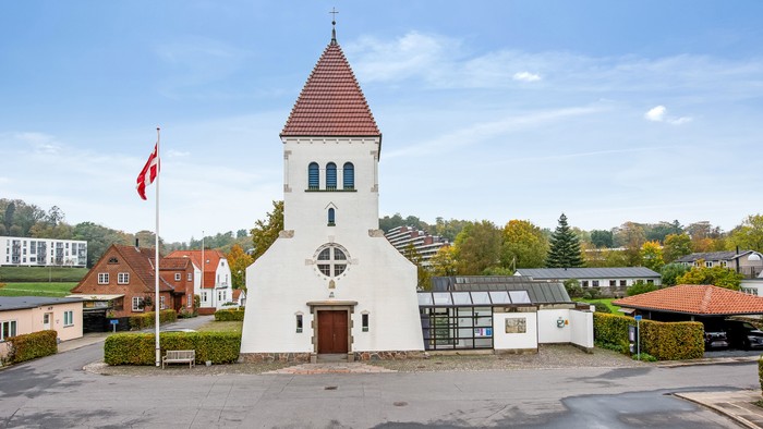 En lille kirke med tårn og en canadisk flag i forgrunden
