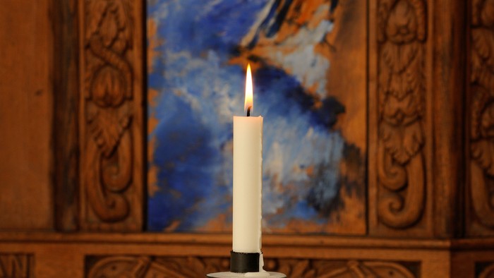 Elegant lysestage på et rundt bord med dekorativt sand og et centralt tændt lys.