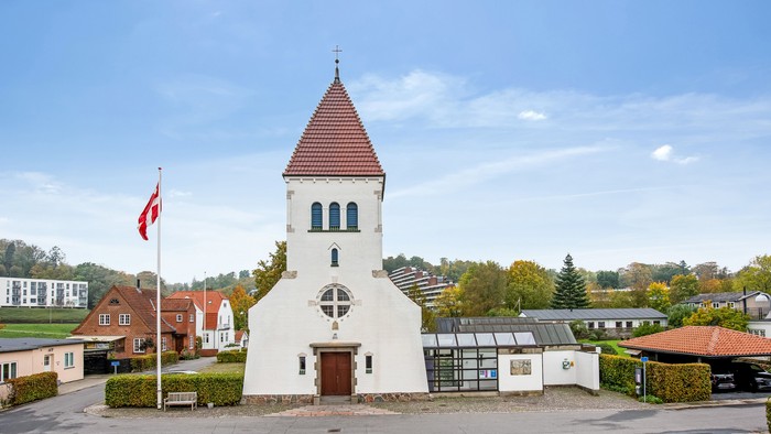 En lille kirke med tårn og en canadisk flag i forgrunden