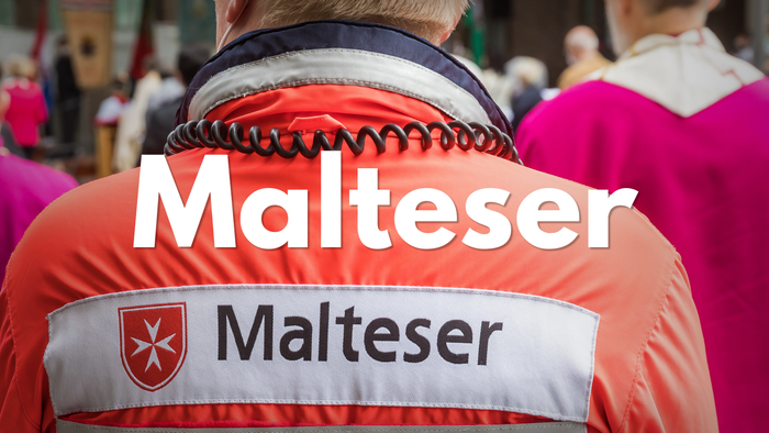 Freiwillige:r in einer orangefarbenen Malteser-Hilfsweste mit dem Emblem und Namen der Organisation.