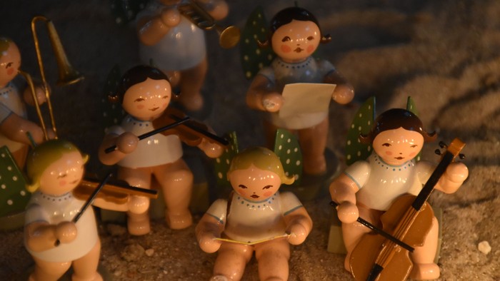 Eine Gruppe von Holzfiguren spielt Musik, darunter ein Geigenspieler und ein Trompeter