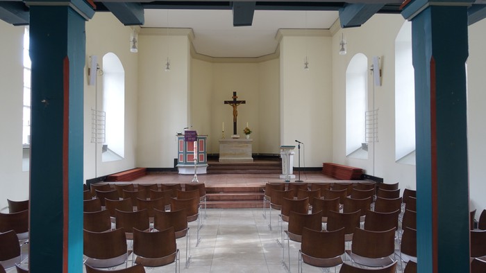 Kleine Kirche mit Holzstühlen und Kreuz am Altar