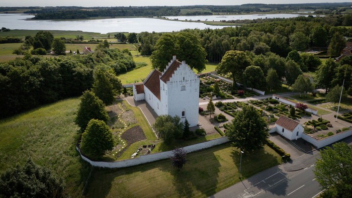 En hvid slot med røde tag i en grøn og træfattig omgivelse ved en sø