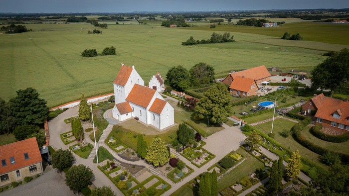 En lille landsby med hvide og røde huse i en grøn og åben landskab