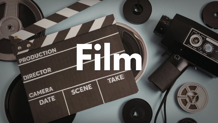 Vintage-Filmklappe umgeben von alten Filmrollen und einer klassischen Kamera, die die Filmproduktion symbolisiert.