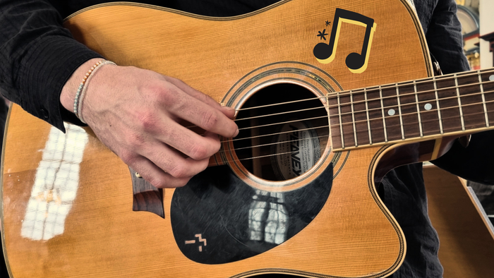En musiker spiller guitar, mens andre optræder i en kirke med klassiske instrumenter og kor.