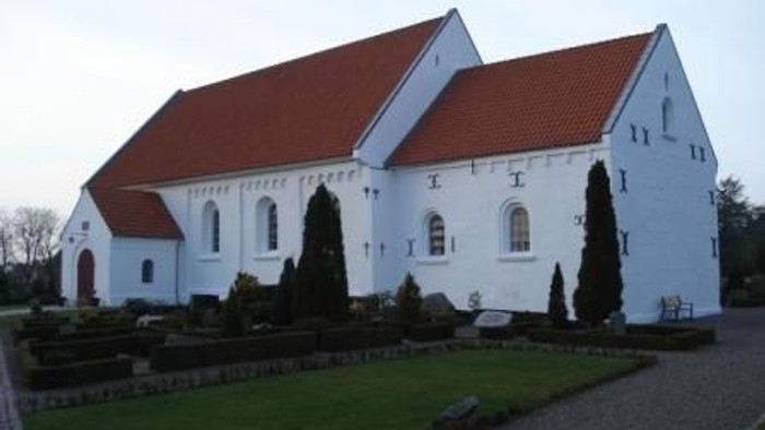 Et hvidt kirkebygning med røde tag og en smukt have foran