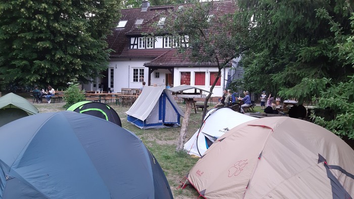 Zelte vor einem Haus mit Menschen, die sitzen