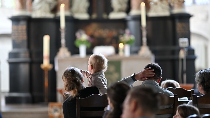 Ein feierlicher Gottesdienst in der Kirche, bei dem ein Kind hochgehoben wird, um den Altar und die Dekorationen zu sehen.