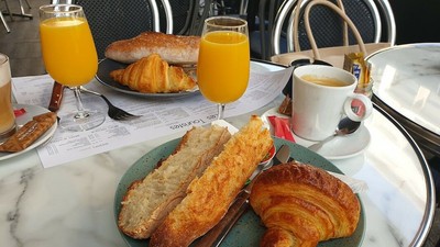 Ein Frühstücksbuffet mit Gebäck, gerösteten Baguettescheiben, Orangensaft und Kaffee auf einem Tisch.