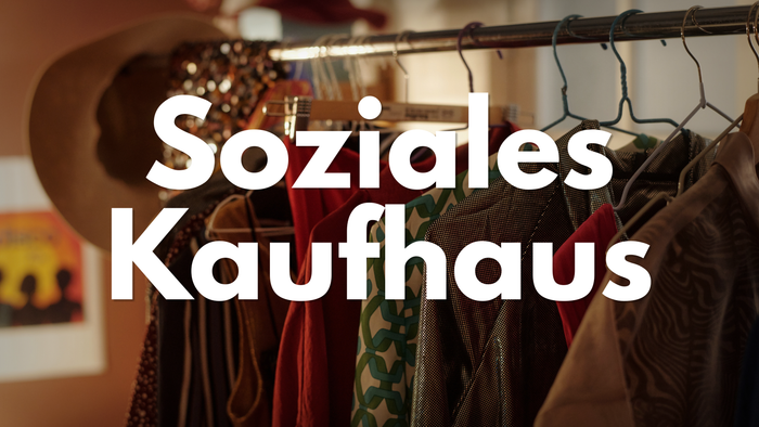 Ein Kleiderständer in einem Sozialkaufhaus mit verschiedenen Hüten und Kleidungsstücken.