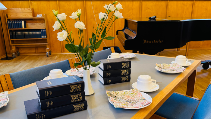 Elegant mødelokale med vintage-bøger, klaver, blomsterdekoration og fint porcelænste-sæt på bordet.