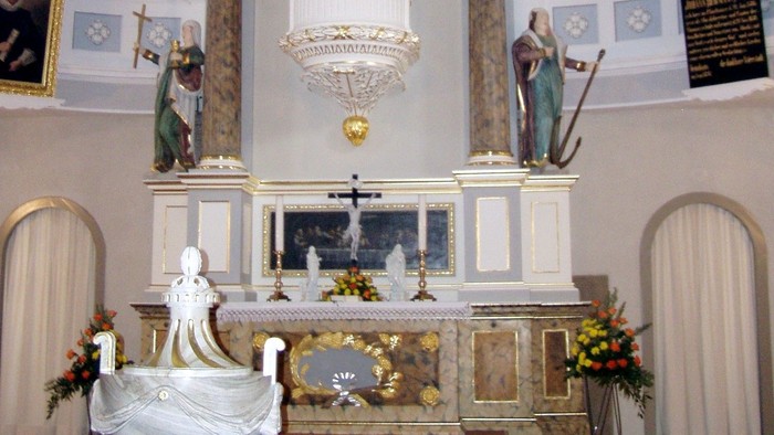 Eleganter Kirchenaltar, geschmückt mit Statuen, goldenen Akzenten und religiösen Verzierungen unter einer sonnenstrahlenden Decke.