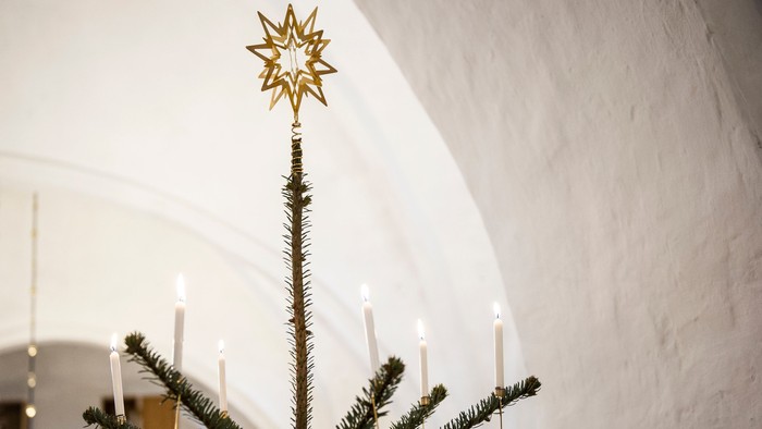 Juletræ med levende lys og stjerne, i en kirke.