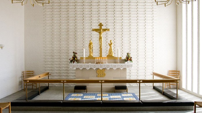 Alter i kirke med guldfarvet krucifix og lysestake