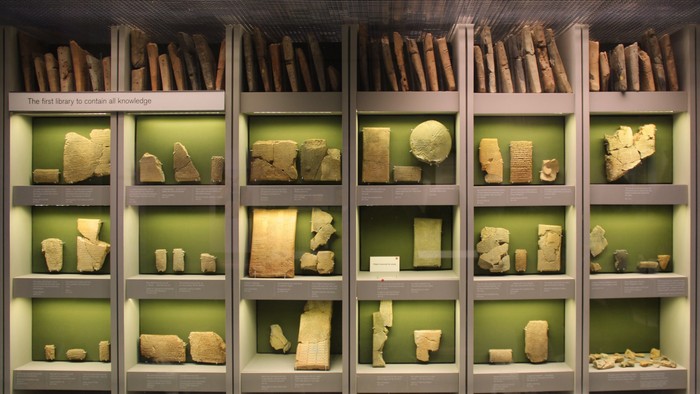 Gamle lerkunstgenstande og mursten udstillet på et museum med informative skilte.