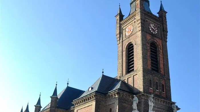 Das Bild zeigt eine große, historische Kirche mit hohem Turm und Uhr.
