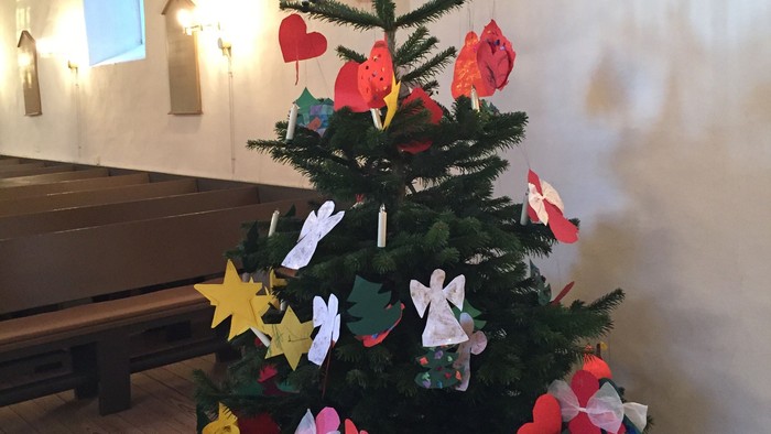 En lille juletree med papirdekorationer i kirke.