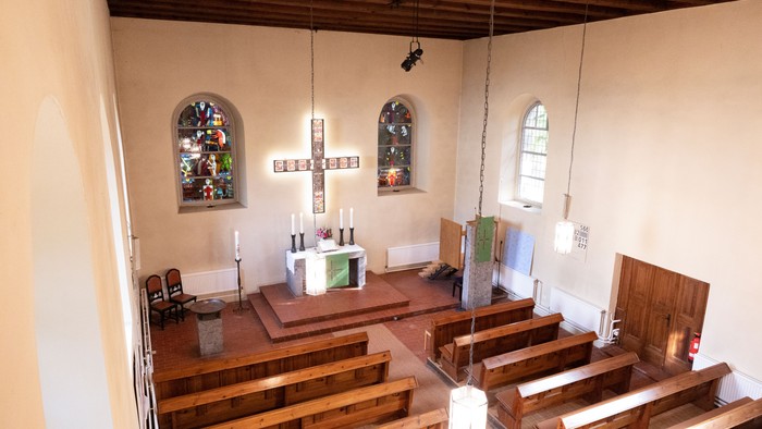 Kleine Kirche mit Holzgestühl und zwei buntverglasten Fenstern