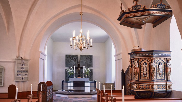 Indre del af kirke med alter, lysestager og pulpet