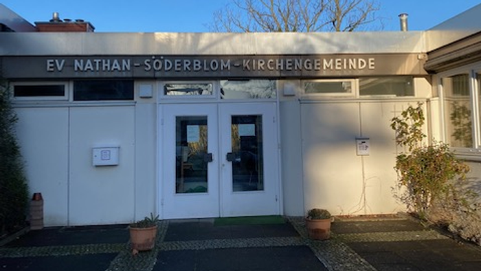 Das Gebäude der EV Nathan-Söderblom-Kirchengemeinde mit Eingangstür und Topfblumen.