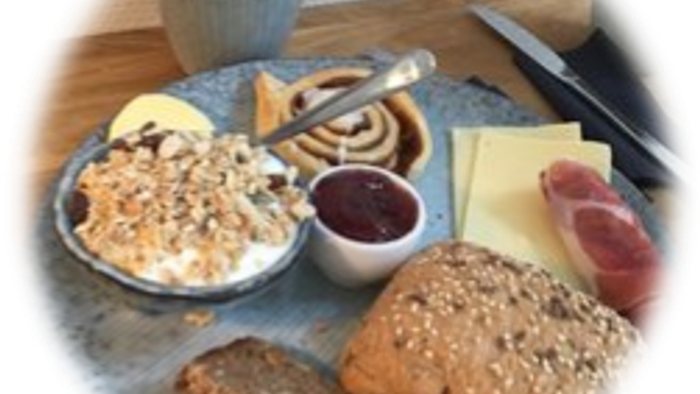 En smørrebrød bord med røgt og ost, koldbrød og chokolade.