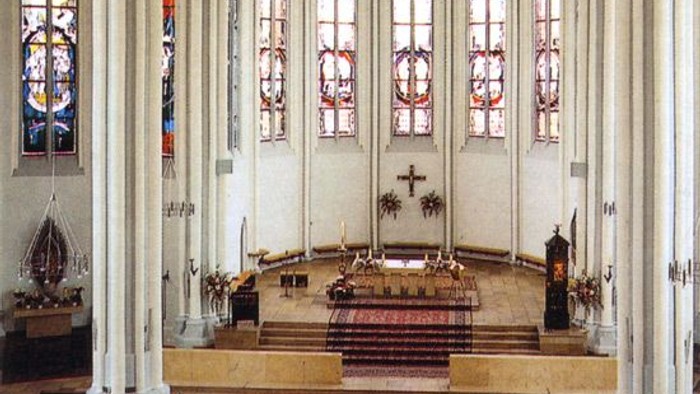 Innenraum einer Kirche mit hohen Säulen und buntem Glasfenster