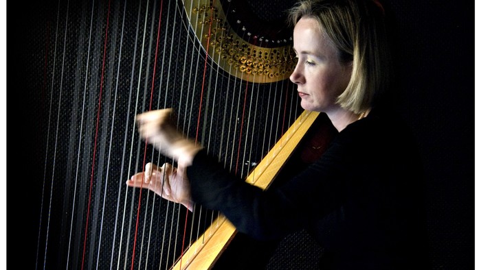 En kvinde spiller harpe i mørkt rum