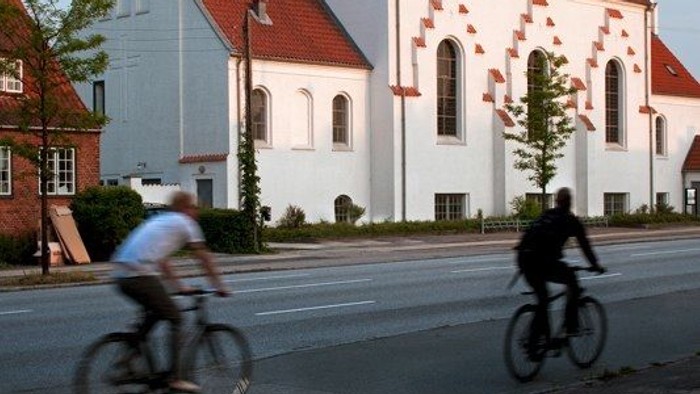 To cykler forbi hvide kirke med røde tag