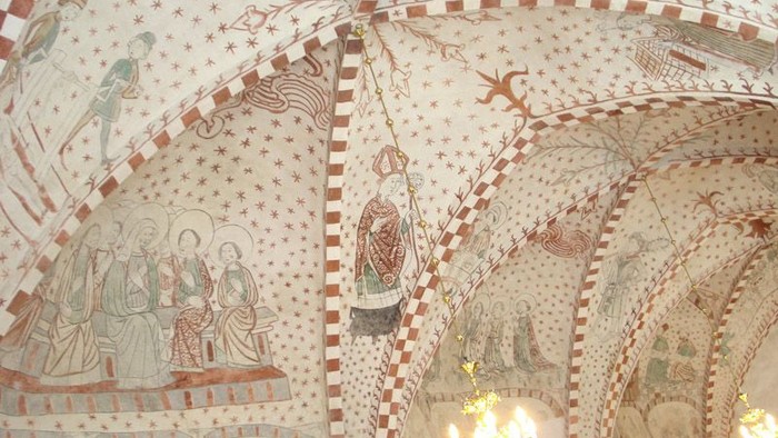 Billedet viser indvendige vægge med malerier og mønstre i kirke.