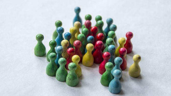 Bunte Holzfiguren in verschiedenen Größen und Farben auf weißem Hintergrund.