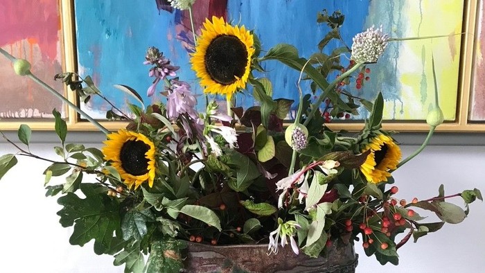 En blomsterstang i en metalløs på en sort bord med en blå maleri på veggen bagud